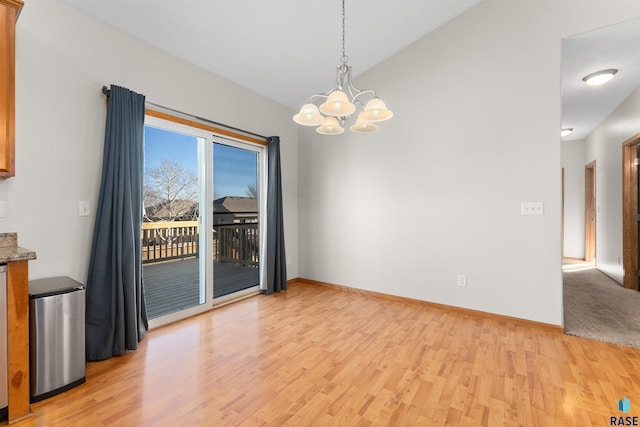 unfurnished dining area featuring lofted ceiling, an inviting chandelier, and light hardwood / wood-style floors