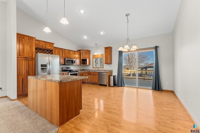 kitchen featuring sink, appliances with stainless steel finishes, a kitchen island, pendant lighting, and light hardwood / wood-style floors