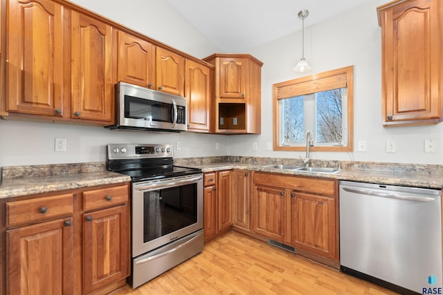 kitchen featuring appliances with stainless steel finishes, light hardwood / wood-style floors, sink, and hanging light fixtures