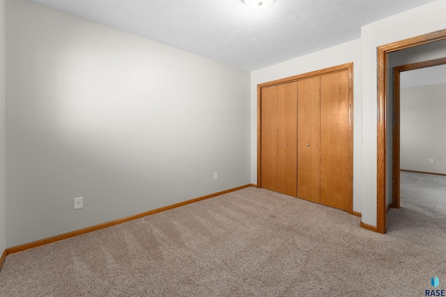 unfurnished bedroom featuring light carpet, a textured ceiling, and a closet