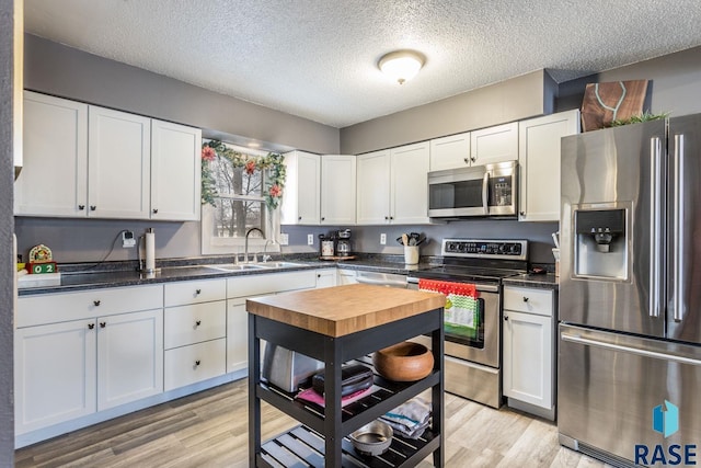 kitchen featuring stainless steel appliances, sink, white cabinets, and light hardwood / wood-style floors