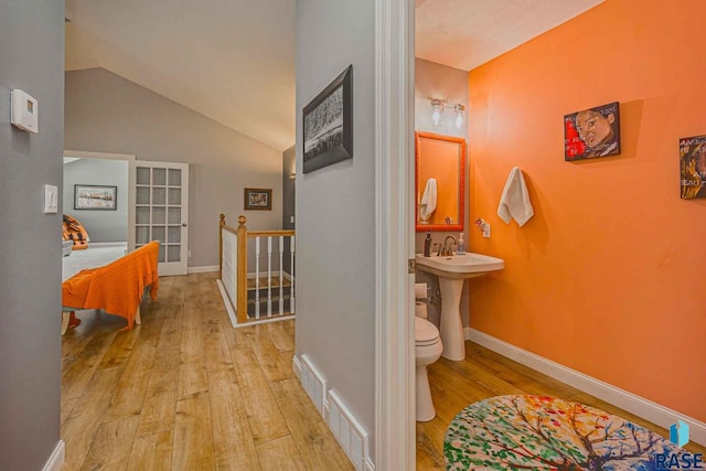 hall with lofted ceiling and light hardwood / wood-style flooring