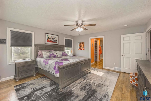 bedroom featuring ceiling fan, a textured ceiling, and dark hardwood / wood-style flooring