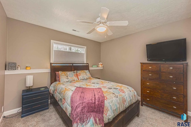 carpeted bedroom featuring ceiling fan and a textured ceiling