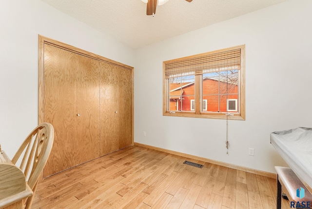 unfurnished bedroom with ceiling fan, a closet, light hardwood / wood-style floors, and a textured ceiling