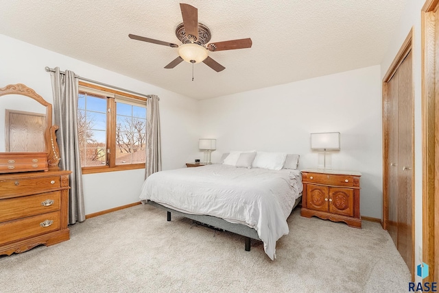 carpeted bedroom featuring ceiling fan, a closet, and a textured ceiling