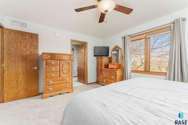 carpeted bedroom with ceiling fan and a textured ceiling