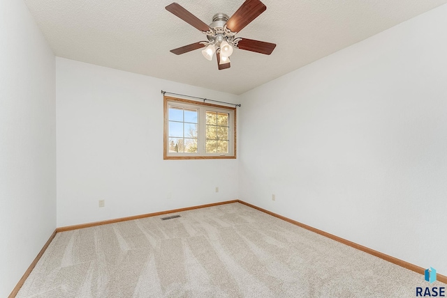 unfurnished room with ceiling fan, light carpet, and a textured ceiling