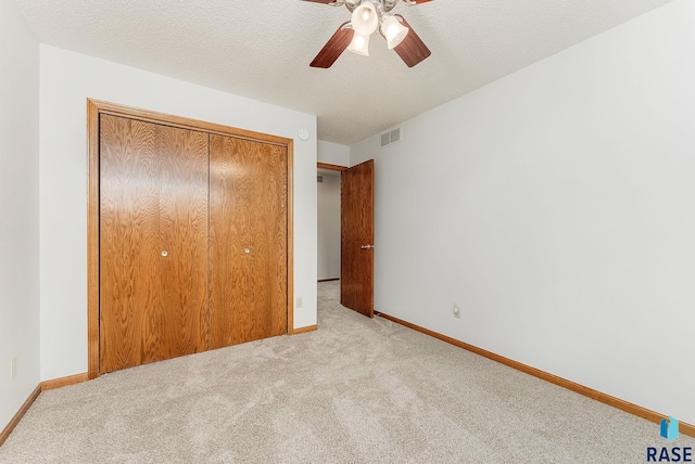 unfurnished bedroom featuring a closet, light carpet, and a textured ceiling