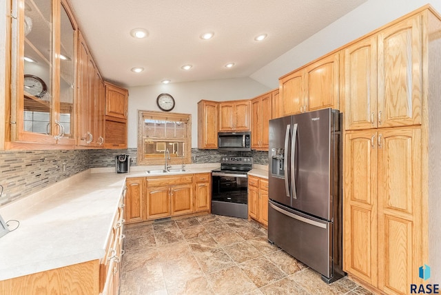 kitchen featuring vaulted ceiling, appliances with stainless steel finishes, sink, and backsplash