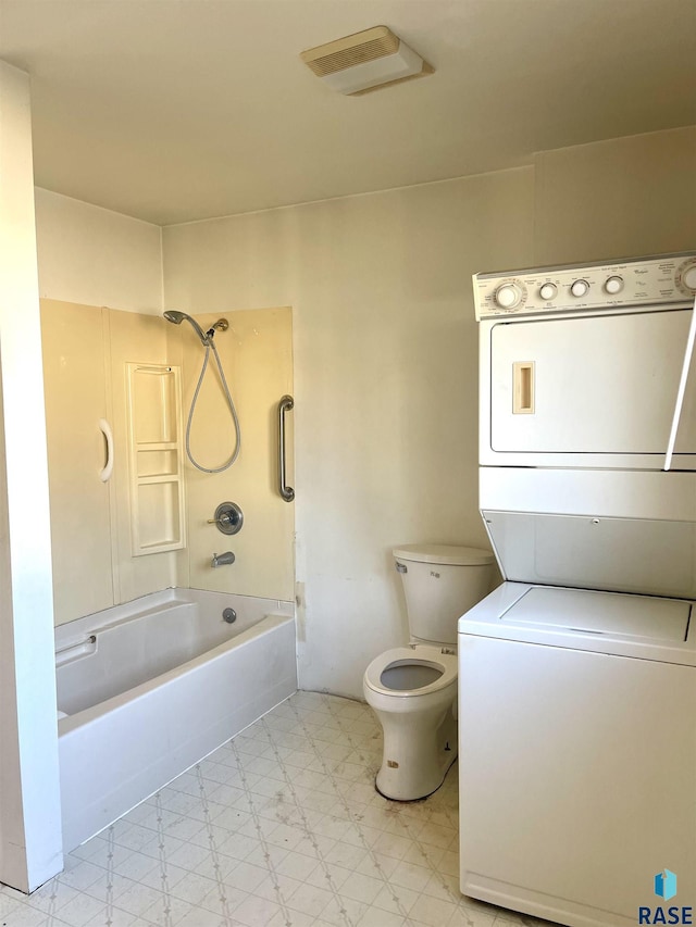 bathroom with stacked washer and dryer, shower / bath combination, and toilet