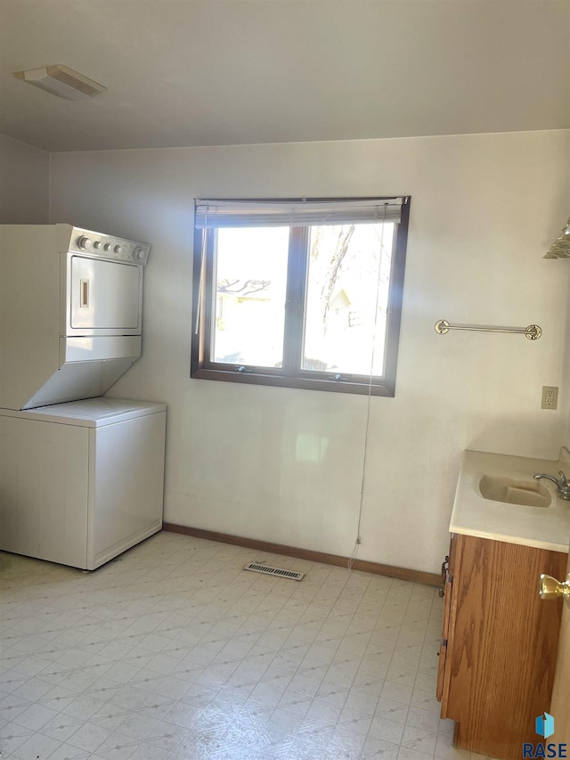 laundry area featuring stacked washer and clothes dryer and sink