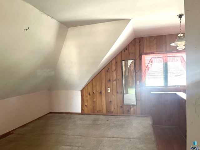 additional living space with vaulted ceiling and wood walls