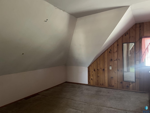 additional living space with wood-type flooring, lofted ceiling, and wood walls