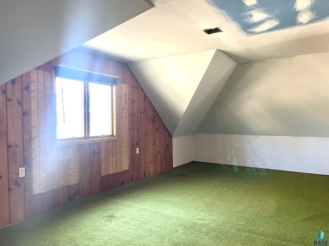 bonus room featuring wooden walls, vaulted ceiling, and carpet flooring