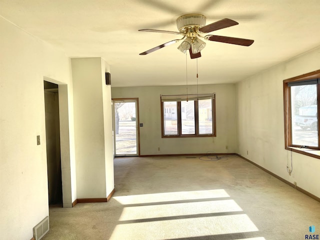 carpeted spare room featuring a wealth of natural light and ceiling fan