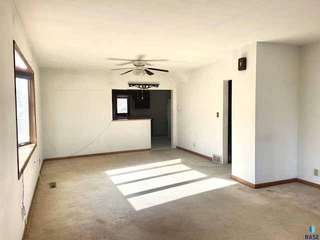 carpeted spare room featuring plenty of natural light and ceiling fan