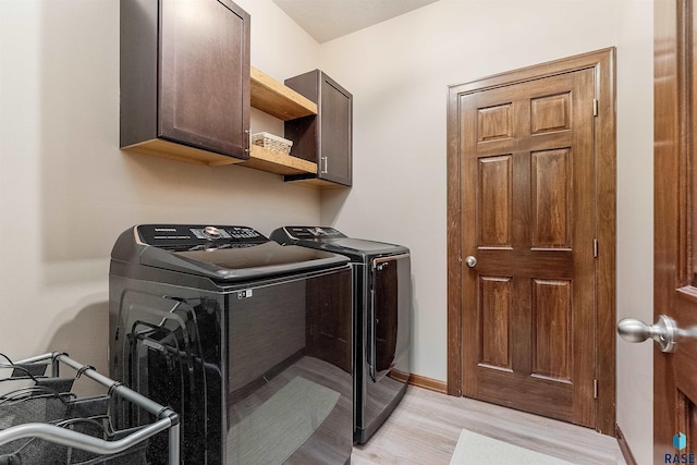 clothes washing area with cabinets, separate washer and dryer, and light hardwood / wood-style flooring