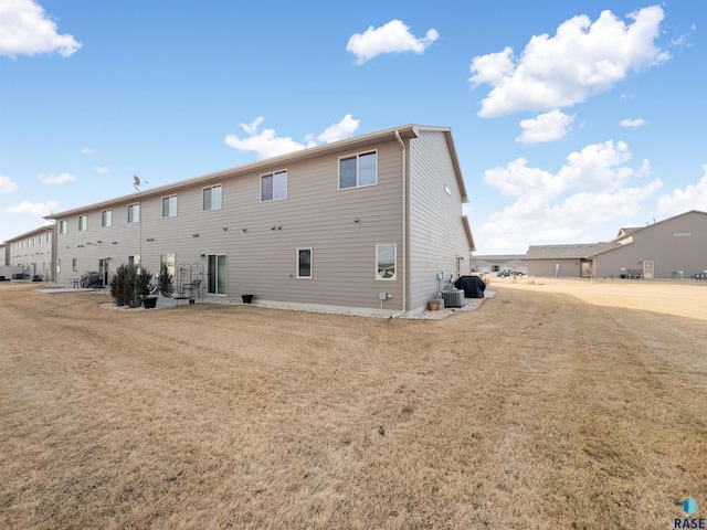 rear view of house featuring cooling unit and a yard