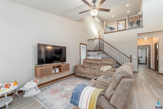 living room featuring light hardwood / wood-style flooring, ceiling fan, and a high ceiling