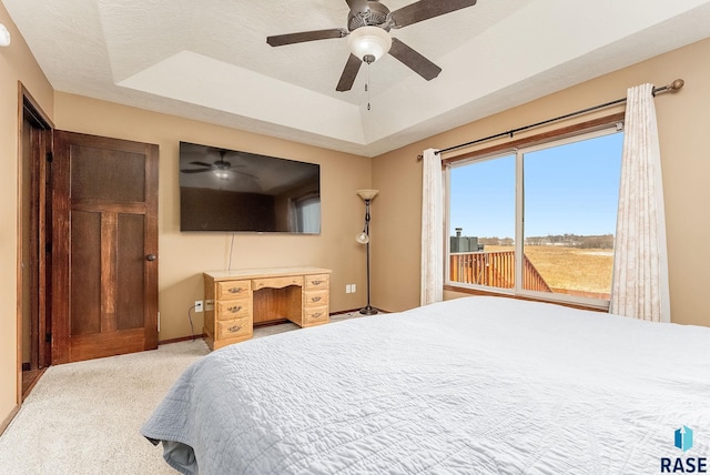 carpeted bedroom with a tray ceiling, a textured ceiling, and ceiling fan