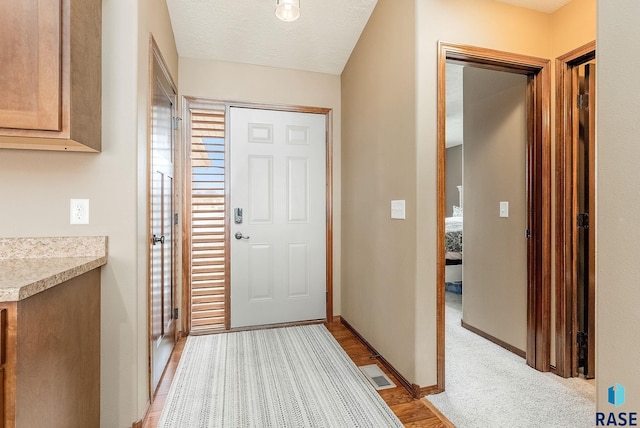 entrance foyer with a textured ceiling and light hardwood / wood-style flooring