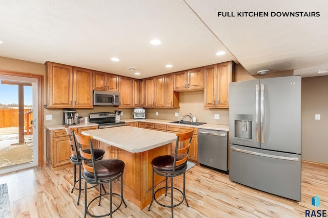 kitchen featuring stainless steel appliances, a kitchen island, sink, and light hardwood / wood-style floors