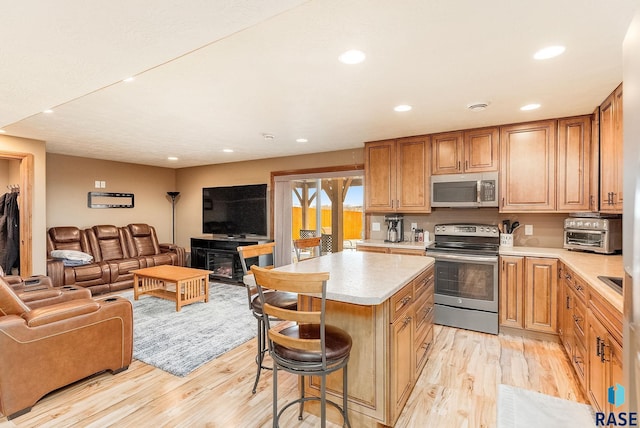 kitchen with a kitchen bar, light hardwood / wood-style floors, a center island, and appliances with stainless steel finishes