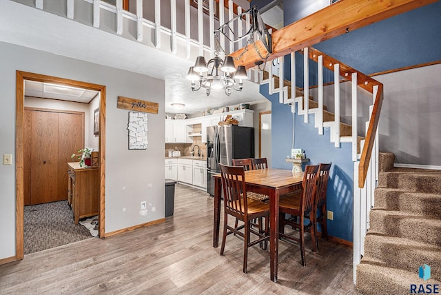 dining area with hardwood / wood-style floors, a towering ceiling, sink, and a chandelier