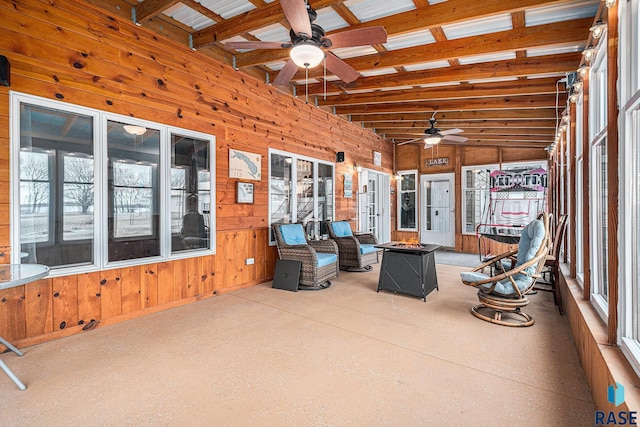 unfurnished sunroom featuring beamed ceiling and ceiling fan