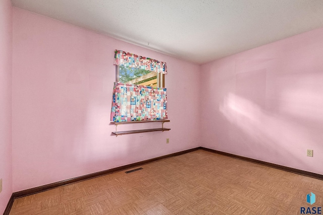 empty room featuring light parquet flooring and a textured ceiling