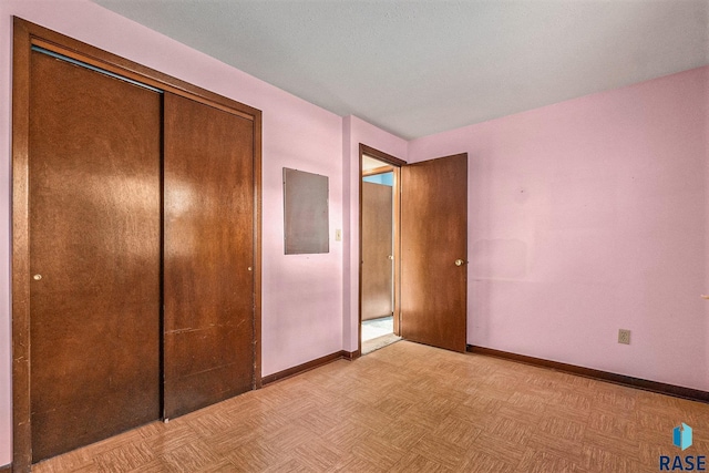 unfurnished bedroom with light parquet flooring, electric panel, and a closet