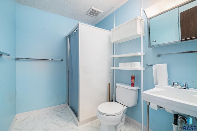 bathroom featuring sink, a shower, toilet, and a textured ceiling