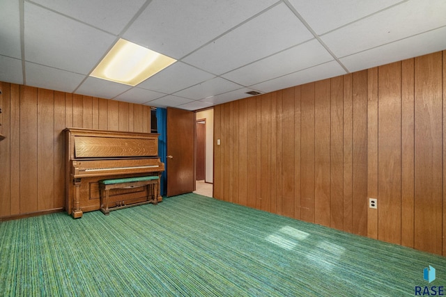 interior space featuring a paneled ceiling and wooden walls