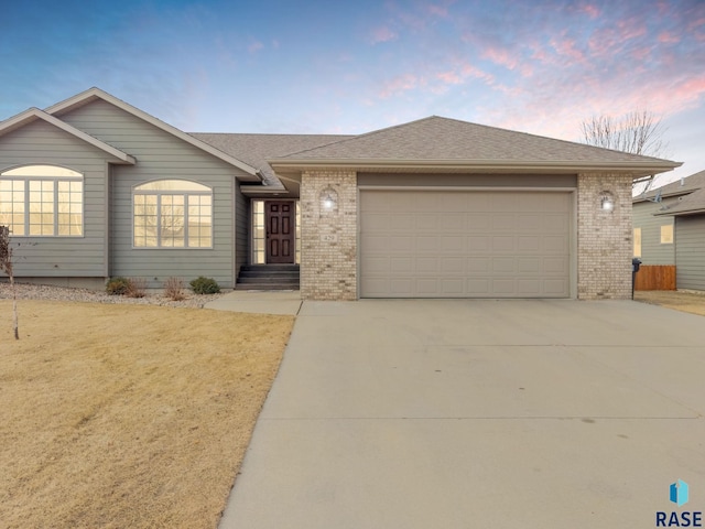 single story home featuring a garage and a lawn