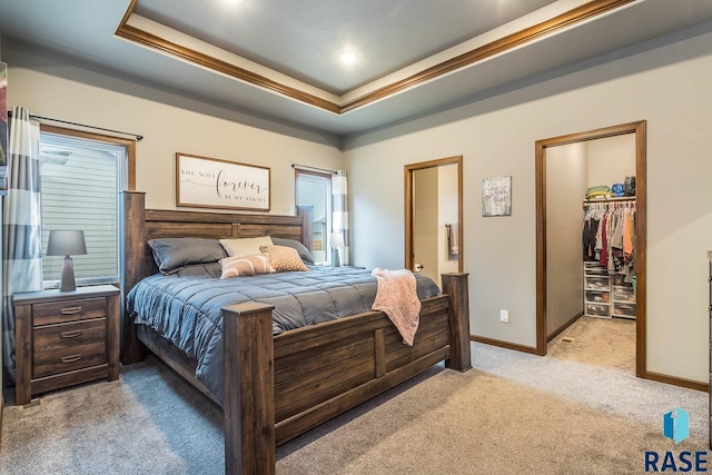 carpeted bedroom with a walk in closet, a raised ceiling, and a closet