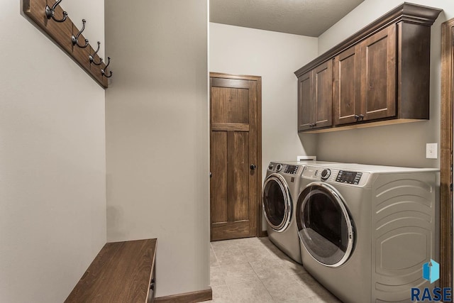 clothes washing area featuring cabinets, separate washer and dryer, light tile patterned floors, and a textured ceiling