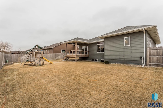 back of house with a playground, a wooden deck, and a yard