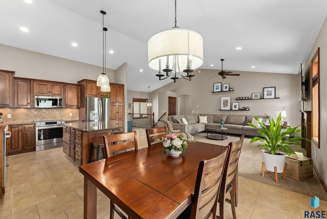 tiled dining room with ceiling fan with notable chandelier and high vaulted ceiling