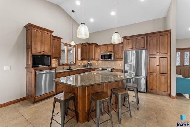 kitchen with sink, dark stone countertops, hanging light fixtures, a center island, and stainless steel appliances