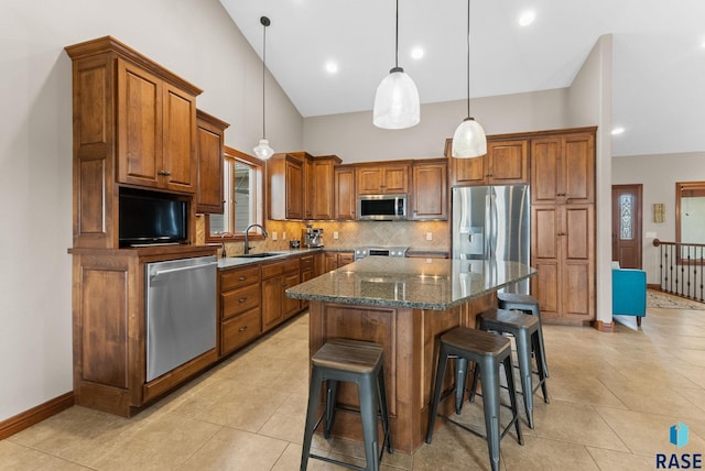 kitchen with pendant lighting, sink, dark stone countertops, a center island, and stainless steel appliances