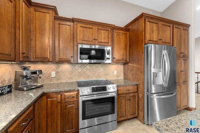 kitchen featuring light stone counters, stainless steel appliances, decorative backsplash, and light tile patterned floors