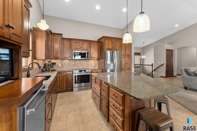 kitchen with a kitchen island, appliances with stainless steel finishes, pendant lighting, a breakfast bar, and sink