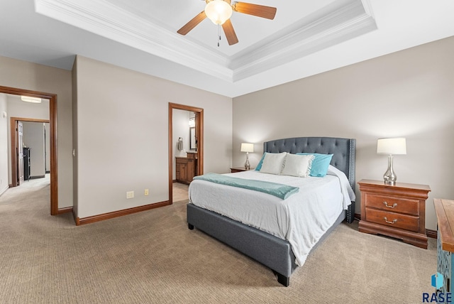 carpeted bedroom with ornamental molding, ensuite bathroom, ceiling fan, and a tray ceiling