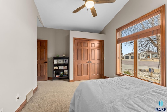 carpeted bedroom with ceiling fan, vaulted ceiling, and a closet