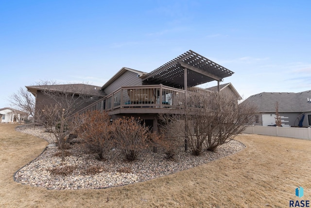 rear view of property with a pergola, a lawn, and a deck