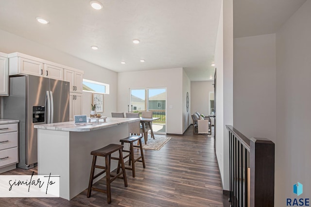 kitchen with a kitchen bar, stainless steel fridge with ice dispenser, dark hardwood / wood-style floors, a kitchen island, and white cabinets