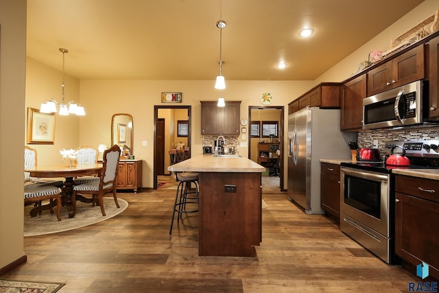 kitchen featuring dark brown cabinetry, a breakfast bar, decorative light fixtures, a kitchen island, and stainless steel appliances