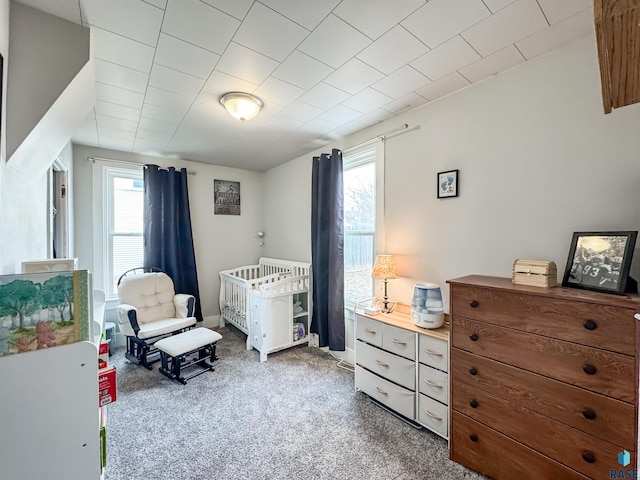 bedroom featuring carpet floors, multiple windows, and a crib