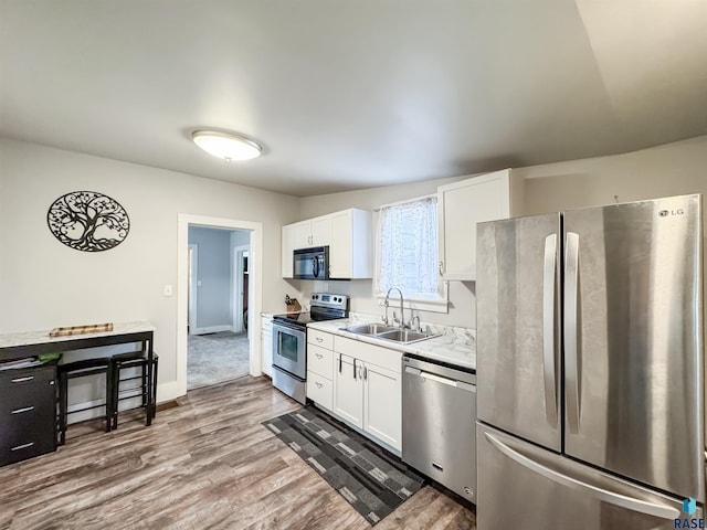 kitchen with sink, wood-type flooring, stainless steel appliances, and white cabinets